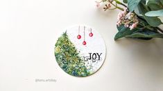 a painted christmas ornament next to a potted plant on a white surface