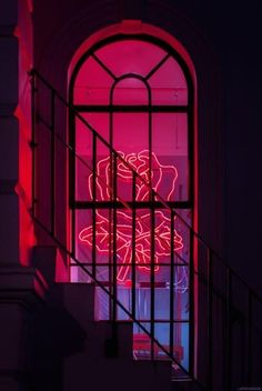 a red neon sign sitting on the side of a window next to a stair case