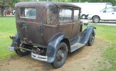 an old car is parked in the grass