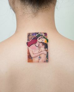 a woman with a tattoo on her back shoulder holding a baby in her arms and looking at the viewer