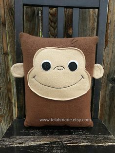 a stuffed monkey pillow sitting on top of a wooden chair