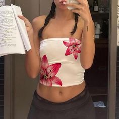 a woman is taking a selfie in the mirror while holding an open book and drinking from a cup