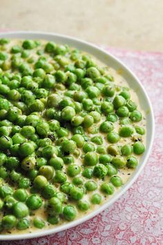 a white bowl filled with peas on top of a table