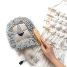 a person is holding a brush next to a hedgehog toy and weaving needles on a white background