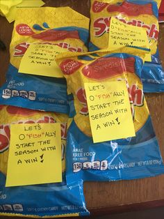 five bags of snacks with sticky notes on them sitting on a table next to a pen