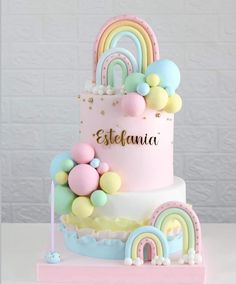 a pink cake with rainbows and balloons on top