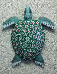 a green turtle with red and white designs on it's shell sitting on the ground