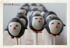 there are many penguin cake pops on the stick with orange noses and nose eyes,