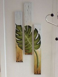 the door is decorated with three wooden panels that have green leaves painted on them, along with a towel rack