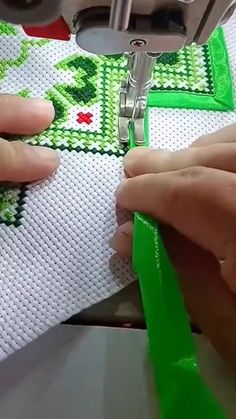 someone is using a sewing machine to sew on a green piece of fabric with scissors