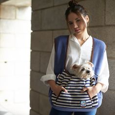 a woman carrying a small dog in a carrier