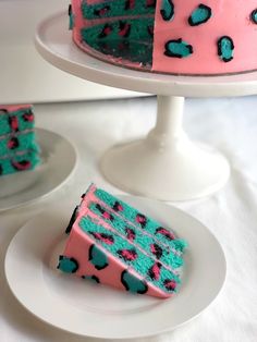 a piece of cake with blue and pink frosting sitting on a plate next to another slice