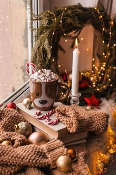 a cup of hot chocolate with marshmallows and candy cane in it sitting on top of a book