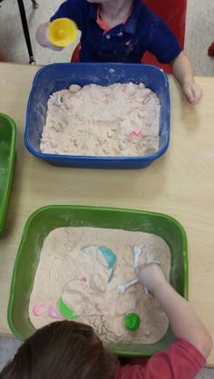 two children sitting at a table making sand