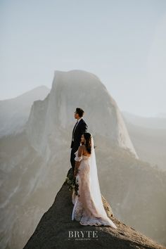 a bride and groom standing on top of a mountain