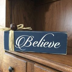 a wooden sign that says believe on it sitting on top of a chest of drawers