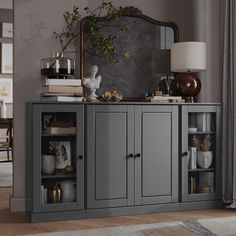 a room with a large mirror on the wall next to a gray cabinet filled with books and vases