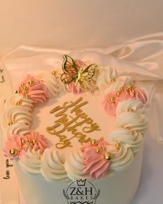 a birthday cake decorated with pink and gold icing on top of a white table