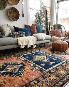 a living room filled with lots of furniture and pillows on top of a large rug