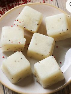 four pieces of white chocolate on a plate with pepper sprinkles next to it