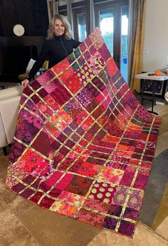 a woman standing next to a colorful quilt