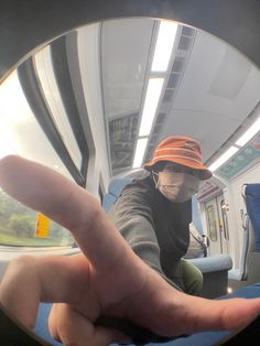 the reflection of a person wearing an orange hat in a round mirror on a train