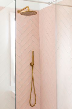 the shower head is gold and has a pink herringbone pattern on it, along with a brass faucet