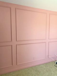 an empty room with pink walls and two laptops on the floor