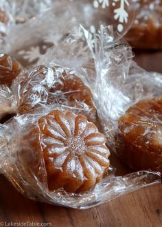 several pieces of fruit wrapped in plastic on a wooden table with snowflakes around them