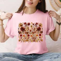 Step into a world of nature-inspired style with our Boho Cottagecore T-shirt, featuring a stunning design of vintage pressed wildflowers. Crafted from 100% soft, breathable cotton, this floral crewneck tee offers comfort and versatility, making it perfect for layering or wearing alone. The natural fibers ensure that you stay cozy while showcasing your love for all things botanical, making it an essential addition to any wardrobe vintage pressed flowers shirt is not only a fashionable choice but Pink Graphic Tee With Plant Print, Pink Graphic Tee With Plants Print, Pink Crew Neck Top With Plant Print, Multicolor Crew Neck T-shirt With Plant Print, Pink T-shirt With Plants Print In Relaxed Fit, Pink T-shirt With Plant Print, Short Sleeve, Botanical Crew Neck Top With Graphic Print, Botanical Printed Crew Neck Top, Fall Crew Neck T-shirt With Plants Print