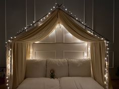 a bed with lights on the headboard and canopy over it in a room that has white walls