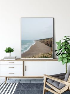 a living room with a chair, plant and large poster on the wall above it