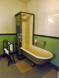 an old fashioned claw foot bathtub in a bathroom with green walls and flooring