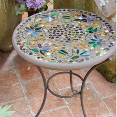 a mosaic table sitting on top of a tiled floor