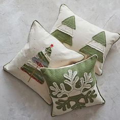 three pillows with christmas trees on them sitting next to each other in front of a white wall