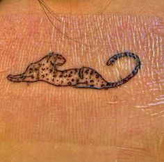 a small tattoo on the back of a woman's stomach, depicting a cheetah