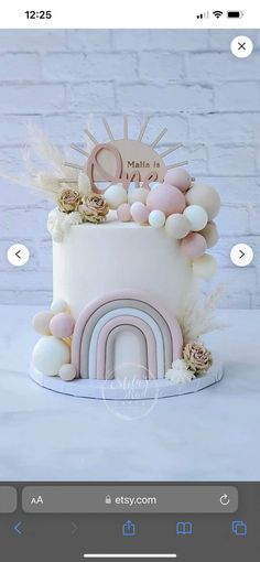 a white cake with pink and gold decorations on it's top, sitting on a table