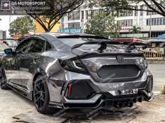 the rear end of a gray car parked in front of a building