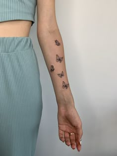 a woman's arm with butterflies tattooed on the left side of her arm,