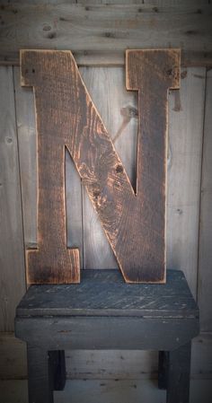 the letter n is made out of wood and sits on a bench in front of a wooden wall