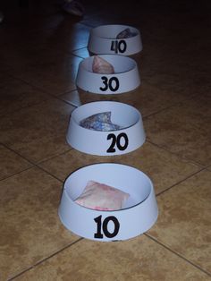 three white bowls with numbers on them sitting on the floor in front of a tile floor