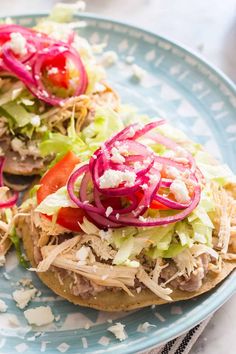 an open faced sandwich topped with lettuce, tomato and onions on a blue plate