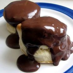 two chocolate covered desserts sitting on top of a white plate with blue trimming