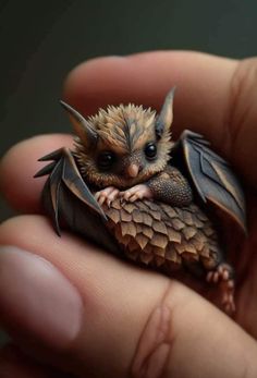 a tiny bat sitting on top of someone's finger in the palm of their hand