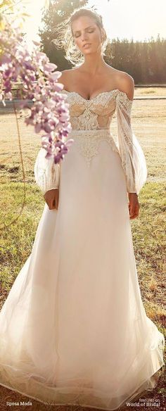 a woman in a wedding dress standing on the grass with her arms behind her back