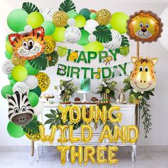 a birthday party with balloons, jungle animals and zebras on the wall in front of it