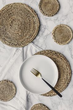 an empty plate with a fork and knife on it next to placemats made from straw