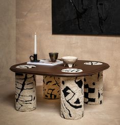 a table with two vases on it in front of a black and white painting