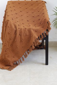 a brown blanket sitting on top of a wooden table next to a potted plant