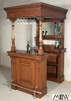 an old fashioned bar with wine glasses on the top and bottles in front of it